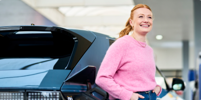 Woman staat naast electrische wagen op een Q8 electric station