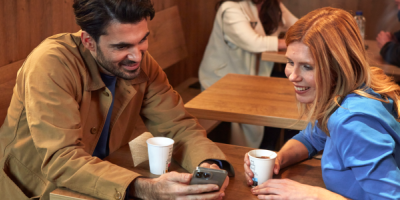 Man en vrouw met starbucks in hun hand aan het kijken naar hun smartphone