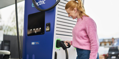 Vrouw trekt stekker van de Q8 electric lader uit om het in haar auto te steken.