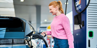 Femme charge sa voiture électrique chez Q8 electric