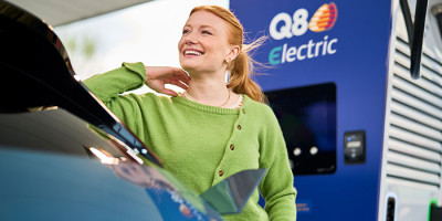 femme sourit a une station de recharge Q8 electric